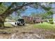 Rear view of brick home with spacious yard and mature trees, featuring a grill, water heater, and convenient parking at 757 Longfellow Rd, Charleston, SC 29407
