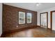 Bedroom with hardwood floors, brick accent wall, and bathroom access at 809 N Magnolia St, Summerville, SC 29483