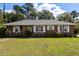 Charming brick home with a well-maintained lawn and traditional white-framed windows and shutters at 809 N Magnolia St, Summerville, SC 29483