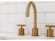 Close-up of gold bathroom faucet with running water and tile backsplash at 83 Avondale Ave, Charleston, SC 29407