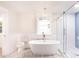 Bright bathroom boasts a modern tub, chandelier, marble floors, and a glass enclosed shower with blue herringbone tile at 83 Avondale Ave, Charleston, SC 29407