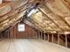 Spacious attic featuring wood floors, insulation, natural light from a window, and ample storage space at 104 Bryant St, Saint George, SC 29477