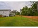 Large backyard with a wooden fence, green grass, covered porch, and wooded area at 107 Belgian Ct, Summerville, SC 29486