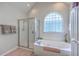 Bright bathroom featuring a glass enclosed shower and large tub with tiled window and privacy glass at 1207 Rivers Reach Dr, Wando, SC 29492