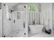 Updated bathroom showcasing a modern, glass-enclosed shower and a separate soaking tub, all enhanced by an arched window at 122 Hidden Fawn Cir, Goose Creek, SC 29445