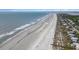 Expansive aerial view of a sandy beach, coastal homes, and the serene ocean waters at 126 W 2Nd St, Folly Beach, SC 29439