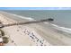 Aerial view of a pier with many beachgoers enjoying the sand and surf, illustrating the lively coastal atmosphere at 126 W 2Nd St, Folly Beach, SC 29439