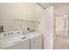 Bright laundry room features a white washer and dryer, wire shelf, and access to a bedroom at 126 W 2Nd St, Folly Beach, SC 29439