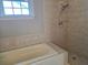 Tiled bath and shower with tiled walls and baseboards, and a window at 133 Wando Reach Rd, Wando, SC 29492