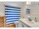 Well-lit bathroom featuring a single sink vanity and a shower with a blue and white striped curtain at 1534 Salisbury St, Charleston, SC 29407