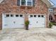 Spacious two-car garage with white doors and classic black iron hardware and a brick exterior at 16 Charlyn Dr, Charleston, SC 29407