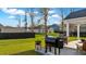 Expansive backyard view showcasing grills, lawn, and houses beyond the black, wooden perimeter fence at 179 Darby Meadow Ln, Ridgeville, SC 29472
