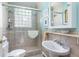Cozy bathroom with light blue walls, a pedestal sink, and a shower with glass block window at 2050 Wappoo Hall Rd, Charleston, SC 29412