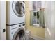 Convenient laundry area with a stacked washer and dryer next to a window with curtains at 2050 Wappoo Hall Rd, Charleston, SC 29412