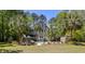 Back exterior of a two-story gray home featuring a slide leading to a swimming pool surrounded by mature trees at 2225 Black Oak Court, Mount Pleasant, SC 29466