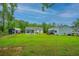 Spacious backyard with lush green grass, pool, sheds, and the rear view of the house at 229 Twin Lake Dr, Summerville, SC 29483