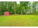 Expansive backyard featuring a red shed and a wooded area, offering ample space for outdoor activities and privacy at 229 Twin Lake Dr, Summerville, SC 29483