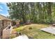 Spacious, fenced backyard featuring a play structure, trampoline, fire pit, and wooded perimeter at 317 Dorchester Manor Blvd, North Charleston, SC 29420