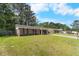 Quaint brick home with a spacious lawn and covered porch on a sunny day at 317 Dorchester Manor Blvd, North Charleston, SC 29420