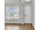 Bright living room with wood floors, large window, and freshly painted white door and walls at 319 Abercom Place Dr, Moncks Corner, SC 29461