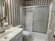 Bathroom featuring a shower over tub, vanity, toilet, tile floor, and patterned wall covering at 36 Forde Row, Charleston, SC 29412