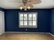 Bedroom featuring stylish blue walls, hardwood floors, a ceiling fan, and bright natural light through shuttered windows at 36 Forde Row, Charleston, SC 29412