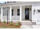 Inviting front porch with white columns, a black front door, and landscaped flowerbeds at 389 Wappoo Trace Ln, Summerville, SC 29486