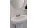 Close-up view of a pedestal sink with a round mirror and stylish chrome fixtures at 394 Flyway Rd, Goose Creek, SC 29445
