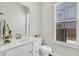 Bright bathroom featuring a white vanity, toilet, mirror, and a window offering natural light at 435 Woodgate Way, Summerville, SC 29485