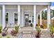 Inviting front porch features classic columns and a charming rocking chair, enhanced by beautiful landscaping at 435 Woodgate Way, Summerville, SC 29485