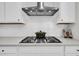 Close-up of a gas cooktop and modern vent hood over white cabinets and subway tile backsplash at 435 Woodgate Way, Summerville, SC 29485