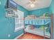 Turquoise bedroom with bunk beds, wood floor, ceiling fan, wall-mounted TV, and window with blinds at 4401 Prices Bridge Ln, Walterboro, SC 29488