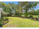 Large, fenced backyard with lush lawn, beautiful trees, and a serene view of the pond at 5258 Mulholland Dr, Summerville, SC 29485