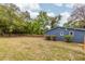 Large backyard with a well-maintained lawn, mature trees, and a blue siding house at 6146 Chisolm Rd, Johns Island, SC 29455