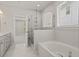 Bright bathroom featuring marble tile, a soaking tub, glass shower, and window at 761 Maynard Ln, Summerville, SC 29486