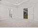 Large bedroom showcasing neutral carpet and paint, a tray ceiling, and doorway to kitchen at 761 Maynard Ln, Summerville, SC 29486