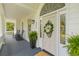 Inviting front porch with rocking chairs, ferns, and an elegant door with decorative wreath at 1 Bay Ct, Isle of Palms, SC 29451