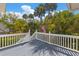 Outdoor deck with grey painted floor overlooking the backyard with tropical trees at 1 Bay Ct, Isle of Palms, SC 29451