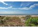 Scenic view of the beach with beautiful sky, plants, and a wooden walkway at 1004 Ocean Blvd # 108, Isle of Palms, SC 29451