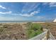 Scenic view of the beach with beautiful sky, plants, and a wooden walkway at 1004 Ocean Blvd # 108, Isle of Palms, SC 29451