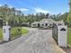Gated entry leading to an estate home featuring a circular drive, manicured landscaping, and mature trees at 1019 Spiers Cir, Bonneau, SC 29431