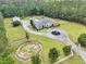 Aerial view of a home showcasing its circular driveway, horse paddock, and lush landscaping surrounded by tall, mature trees at 1019 Spiers Cir, Bonneau, SC 29431