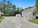 Property view showing a white exterior, gravel driveway, a utility shed, and a three car garage at 1019 Spiers Cir, Bonneau, SC 29431