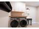 Well-lit laundry room features stainless steel washer/dryer, farmhouse sink, and white cabinets at 117 Lucia St, Charleston, SC 29492