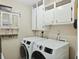 Well-lit laundry room features modern washer and dryer, overhead cabinets, and charming vintage storage unit at 158 Whippoorwill Dr, Summerville, SC 29483