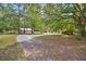 Scenic view of a gravel driveway leading through a spacious yard with mature trees and open skies at 158 Whippoorwill Dr, Summerville, SC 29483