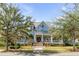 Charming blue home featuring a welcoming front porch, lush lawn and mature trees enhancing curb appeal at 187 Ithecaw Creek St, Daniel Island, SC 29492