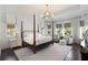 Bright main bedroom with a four-poster bed, dark wood floors, sitting area and large windows with views at 2372 Darts Cove Way, Mount Pleasant, SC 29466