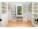 A walk-in closet with white shelving and a built in desk between two windows at 2870 Ion Ave, Sullivans Island, SC 29482