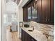 Stylish bar area featuring dark wood cabinetry, granite countertops, mosaic tile backsplash, and open access to dining area at 337 Evian Way, Mount Pleasant, SC 29464